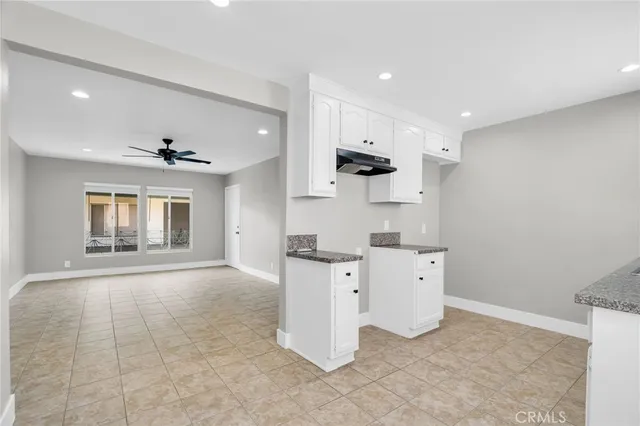 an empty room with a ceiling fan and windows