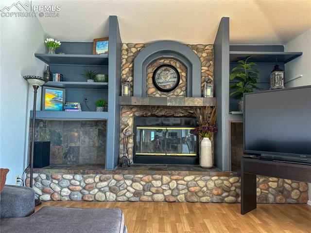 11125 Eureka Road Calhan, CO 80808 - Photo 11 of 44 Living room with a textured ceiling, a fireplace, vaulted ceiling, and hardwood / wood-style floors