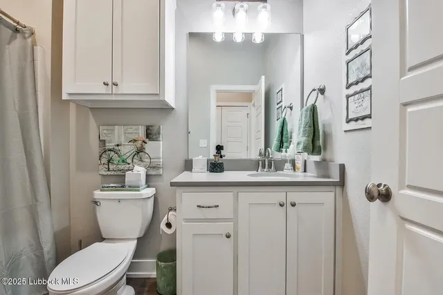 a bathroom with a granite countertop toilet sink and mirror