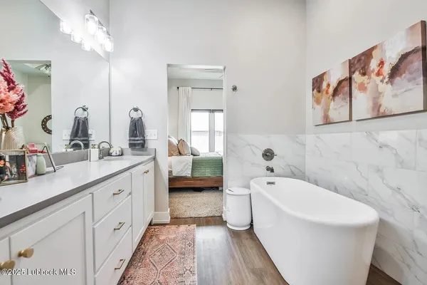 a spacious bathroom with a double vanity sink a mirror a bathtub and