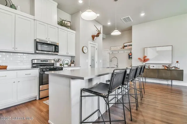 a kitchen with stainless steel appliances kitchen island granite countertop a stove a sink a microwave a dining table and chairs