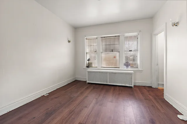 an empty room with wooden floor and a window
