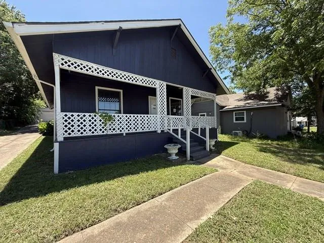 a front view of a house with a garden and trees