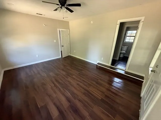 an empty room with wooden floor and a ceiling fan