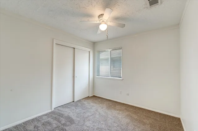 an empty room with a window and a fan