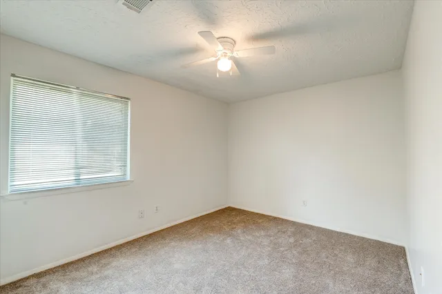 an empty room with a ceiling fan and a window