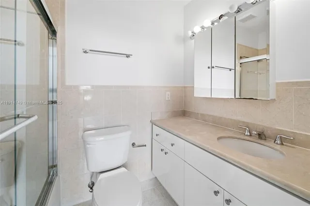 a bathroom with a granite countertop toilet sink and mirror