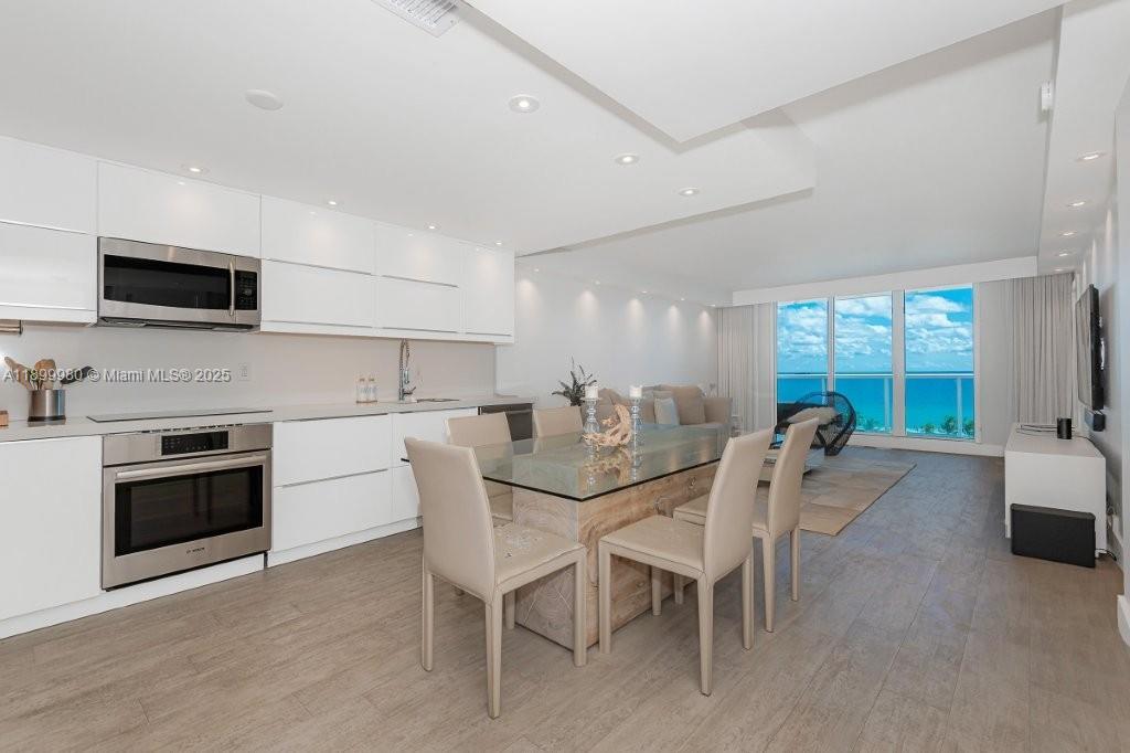 2301 Collins Avenue, Unit 738 Miami Beach, FL 33139 - Photo 5 of 33 a kitchen with stainless steel appliances granite countertop a stove a sink dishwasher a dining table and chairs with wooden floor