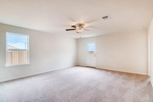 an empty room with a window and a ceiling fan