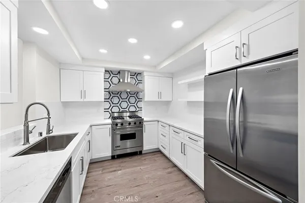 a kitchen with stainless steel appliances granite countertop a sink a stove and refrigerator