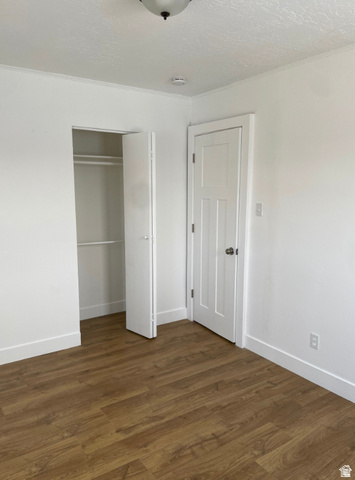 230 North 2nd Street Tooele, UT 84074 - Photo 13 of 18 Room featuring wood-finish flooring, white baseboards, a flush-mount ceiling light, a built-in closet with bifold doors, and a paneled interior door