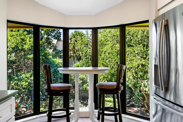 a kitchen with stainless steel appliances granite countertop a stove a refrigerator a sink a dining table and chairs with wooden floor