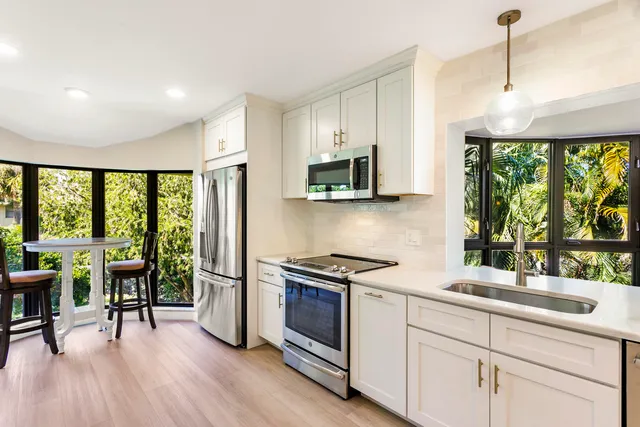 a kitchen with granite countertop a stove top oven a sink a dining table and chairs with wooden floor