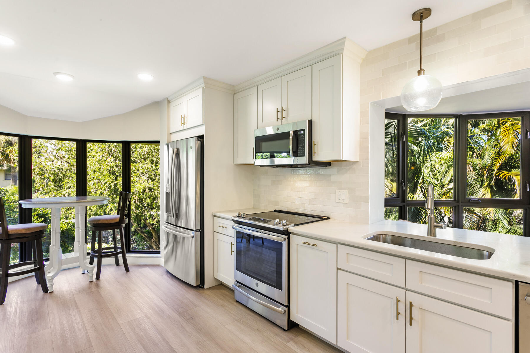 17137 Waterbend Drive, Unit 201 Jupiter, FL 33477 - Photo 12 of 43 a kitchen with stainless steel appliances granite countertop a stove a refrigerator a sink a dining table and chairs with wooden floor