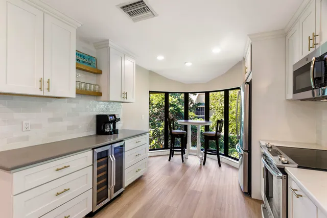 a kitchen with stainless steel appliances a dining table chairs and a refrigerator
