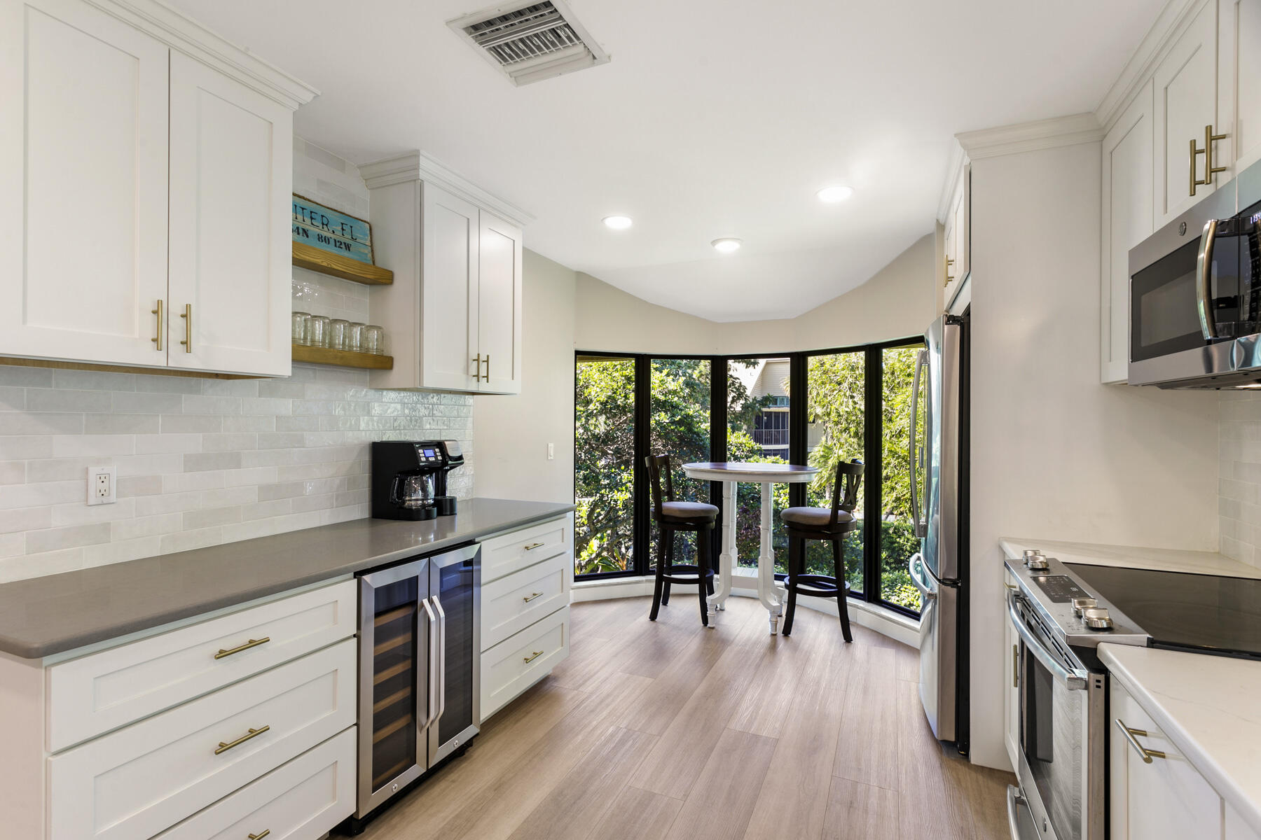 17137 Waterbend Drive, Unit 201 Jupiter, FL 33477 - Photo 13 of 43 a kitchen with granite countertop a stove top oven a sink a dining table and chairs with wooden floor