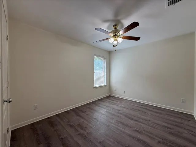 a view of an empty room with window and wooden floor