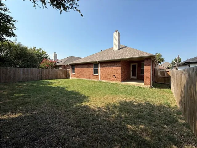 a view of a white house next to a yard with big trees