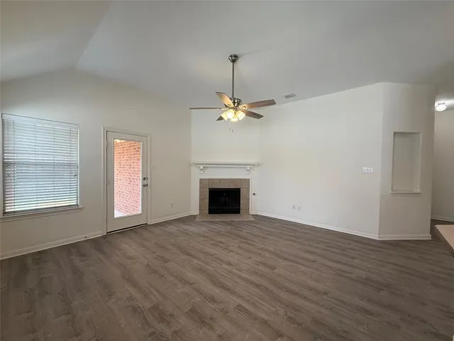 an empty room with wooden floor fireplace and windows