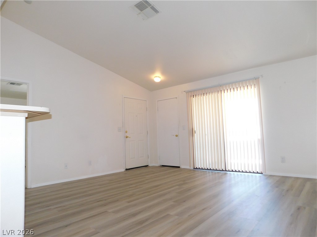 5221 South Lindell Road, Unit 202 Las Vegas, NV 89118 - Photo 9 of 28 Bright vinyl plank flooring extends through this room, featuring vaulted ceilings and a sliding glass door.