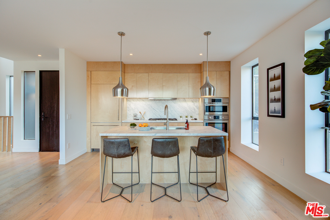 6876 Pacific View Drive Los Angeles, CA 90068 - Photo 9 of 31 a kitchen with kitchen island stainless steel appliances a dining table chairs and wooden floor