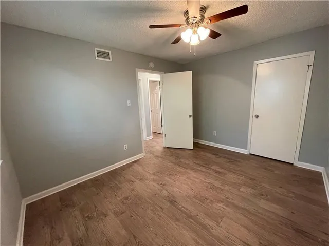 an empty room with wooden floor fan and windows