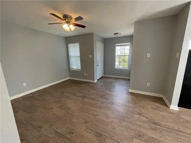 a view of an empty room with window and wooden floor