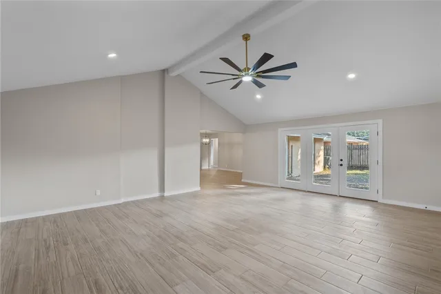 a view of an empty room with a window and wooden floor