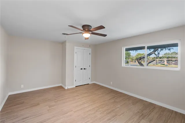 a view of an empty room with a window and wooden floor
