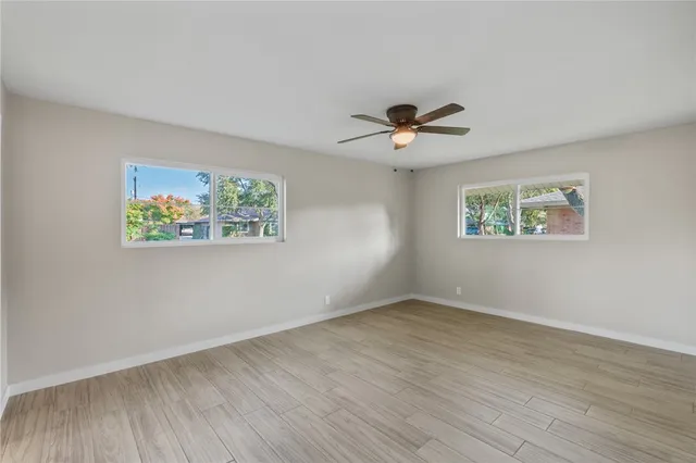 a view of an empty room with a window and wooden floor