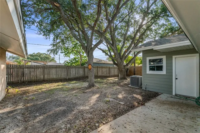 a view of a yard with a large tree and wooden fence