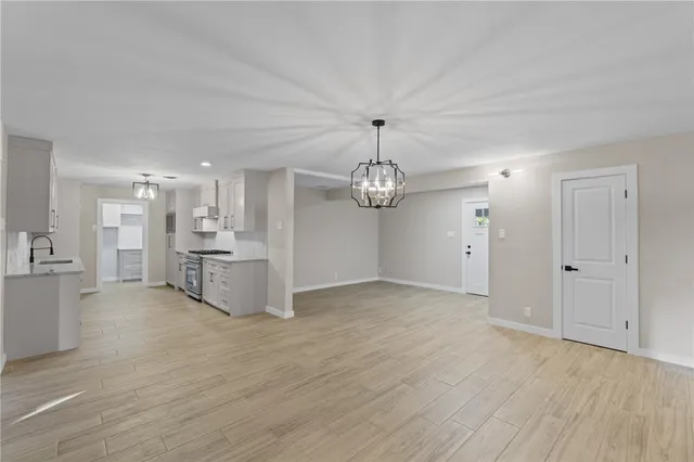 a view of a kitchen with stainless steel appliances refrigerator a microwave oven a stove and white cabinets with wooden floor