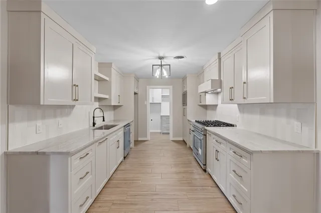 a large kitchen with cabinets stainless steel appliances a sink and a stove