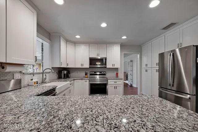 a kitchen with granite countertop a refrigerator and a sink