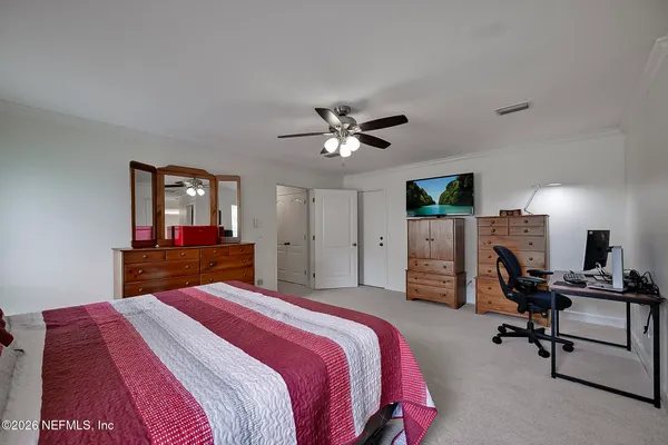 a bedroom with a bed a desk and chair with potted plants