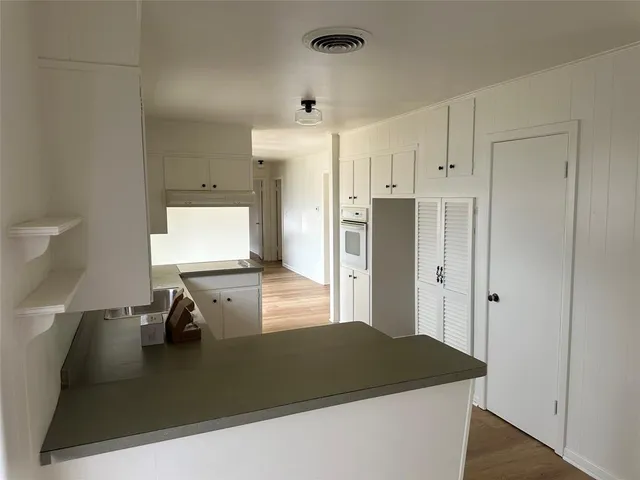 a kitchen with stainless steel appliances granite countertop a refrigerator a sink and white cabinets