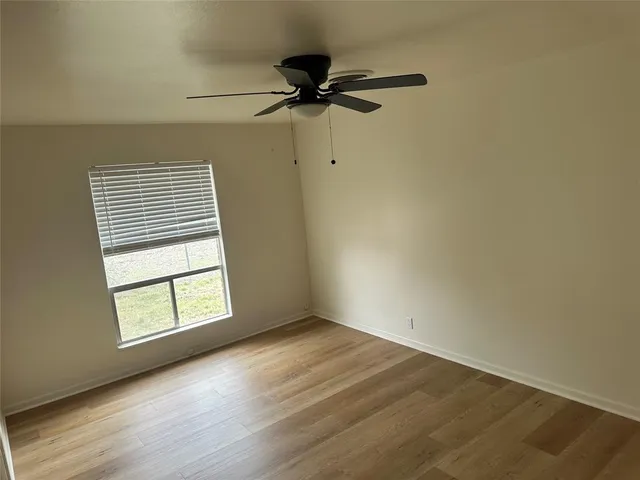 an empty room with a window and a ceiling fan