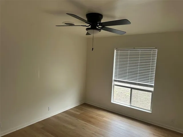 an empty room with wooden floor closet and windows