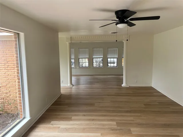 a view of an empty room with wooden floor and a window