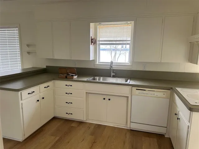 a kitchen with granite countertop white cabinets sink and window