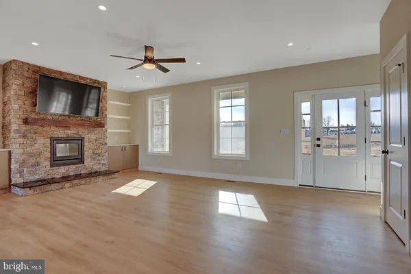 a view of a livingroom with a fireplace a ceiling fan and windows