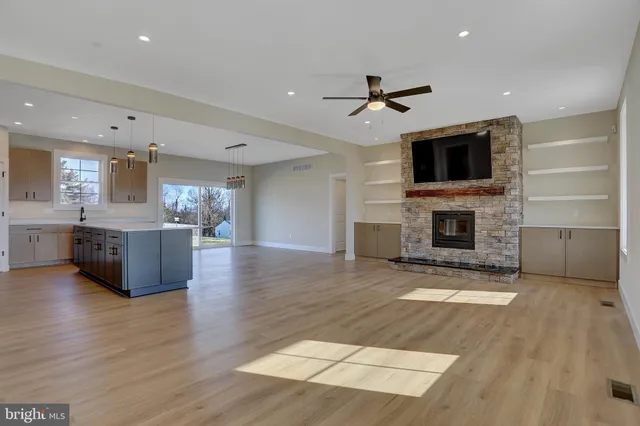 a view of an empty room with a fireplace and a kitchen