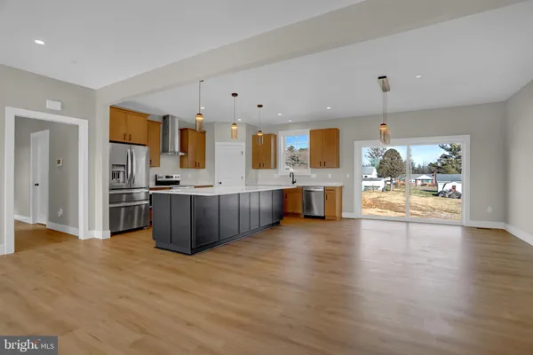 a view of kitchen with kitchen island wooden floor and refrigerator
