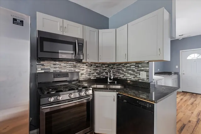 a kitchen with granite countertop a sink stove and microwave