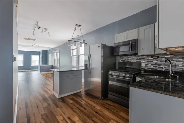 a kitchen with a refrigerator stove and wooden floor