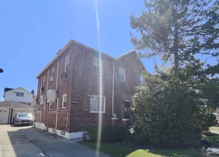 View of side of property with brick siding, an outbuilding, driveway, and a garage