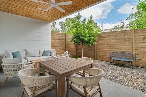 a patio with a table and chairs and potted plants