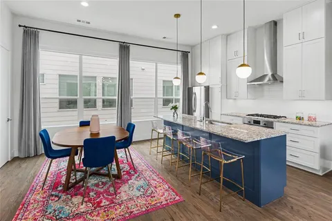 a kitchen with stainless steel appliances granite countertop a stove a sink a dining table and chairs with wooden floor