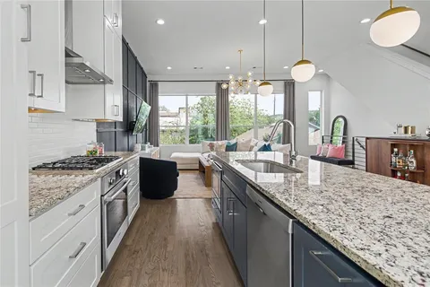 a kitchen with granite countertop a sink a counter top space a stove and cabinets