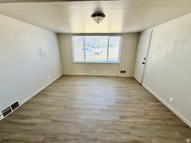 7 Foothill Boulevard Pocatello, ID 83204 - Photo 10 of 13 Spacious room featuring wood-finish flooring, light-colored walls, a large window, a ceiling-mounted light fixture, and white trim